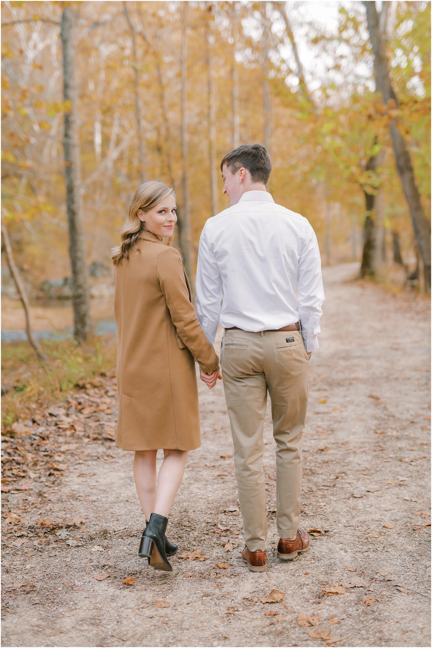 Couple walking in forest autumn engagement session at Great Falls
