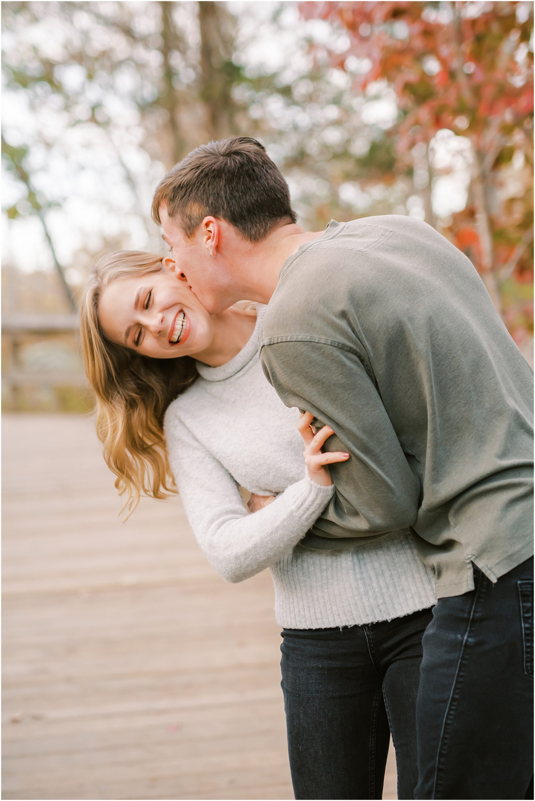 Couple kissing on cheek during autumn engagement session