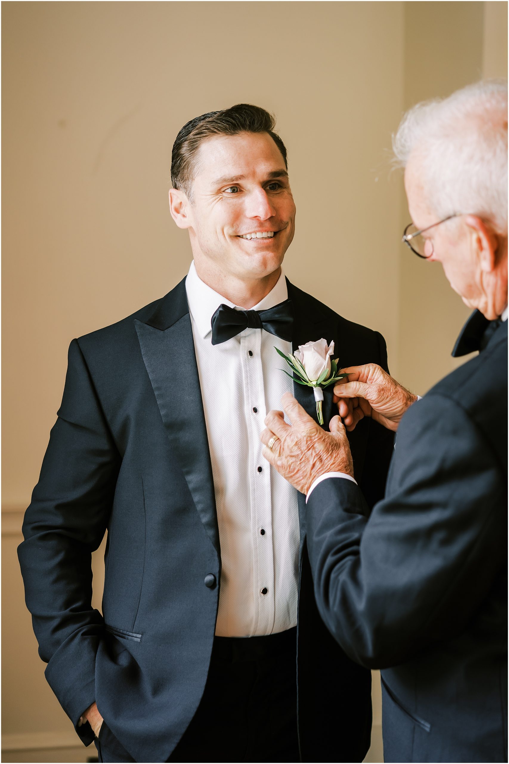 Helping groom pin the boutonniere for wedding at Rust Manor House