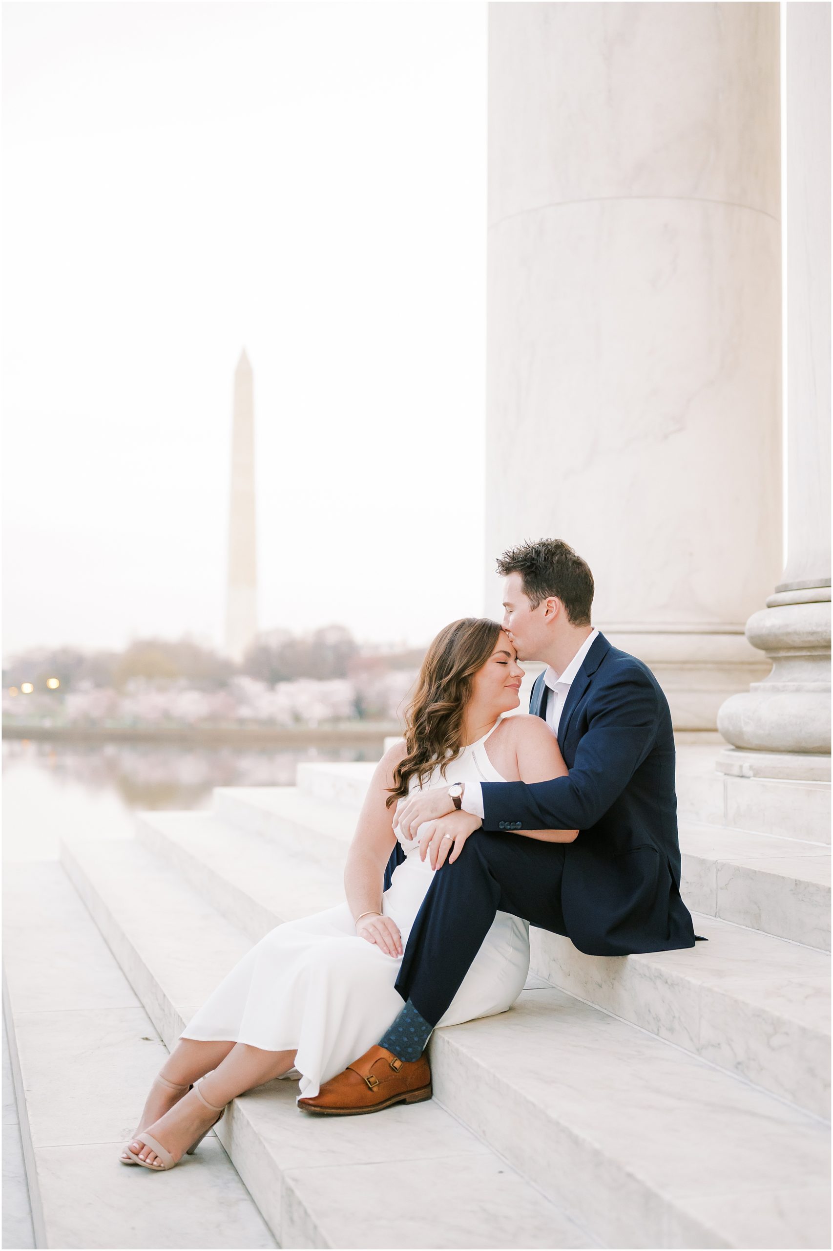 Couple sitting on steps at the Lincoln Memorial with the Washington Monument in the background