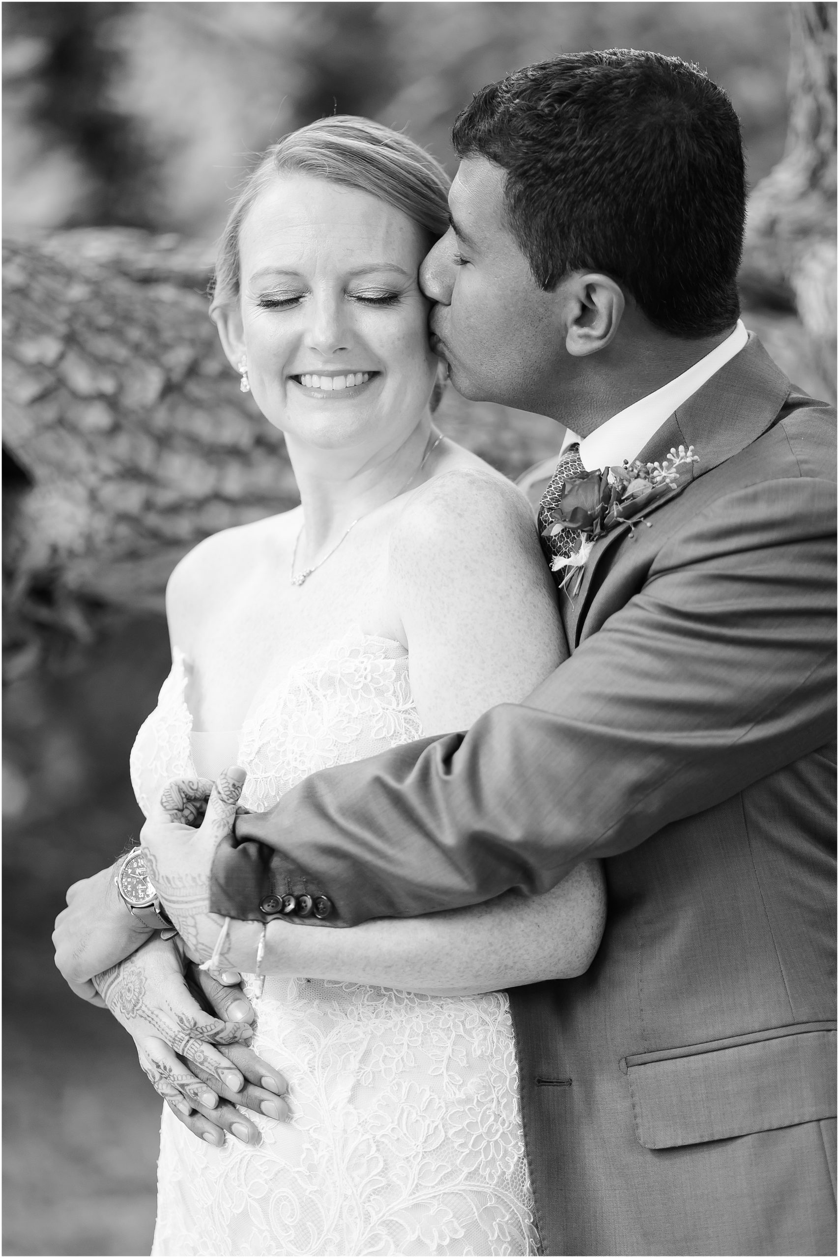 Black and white portrait of groom embracing bride on wedding day
