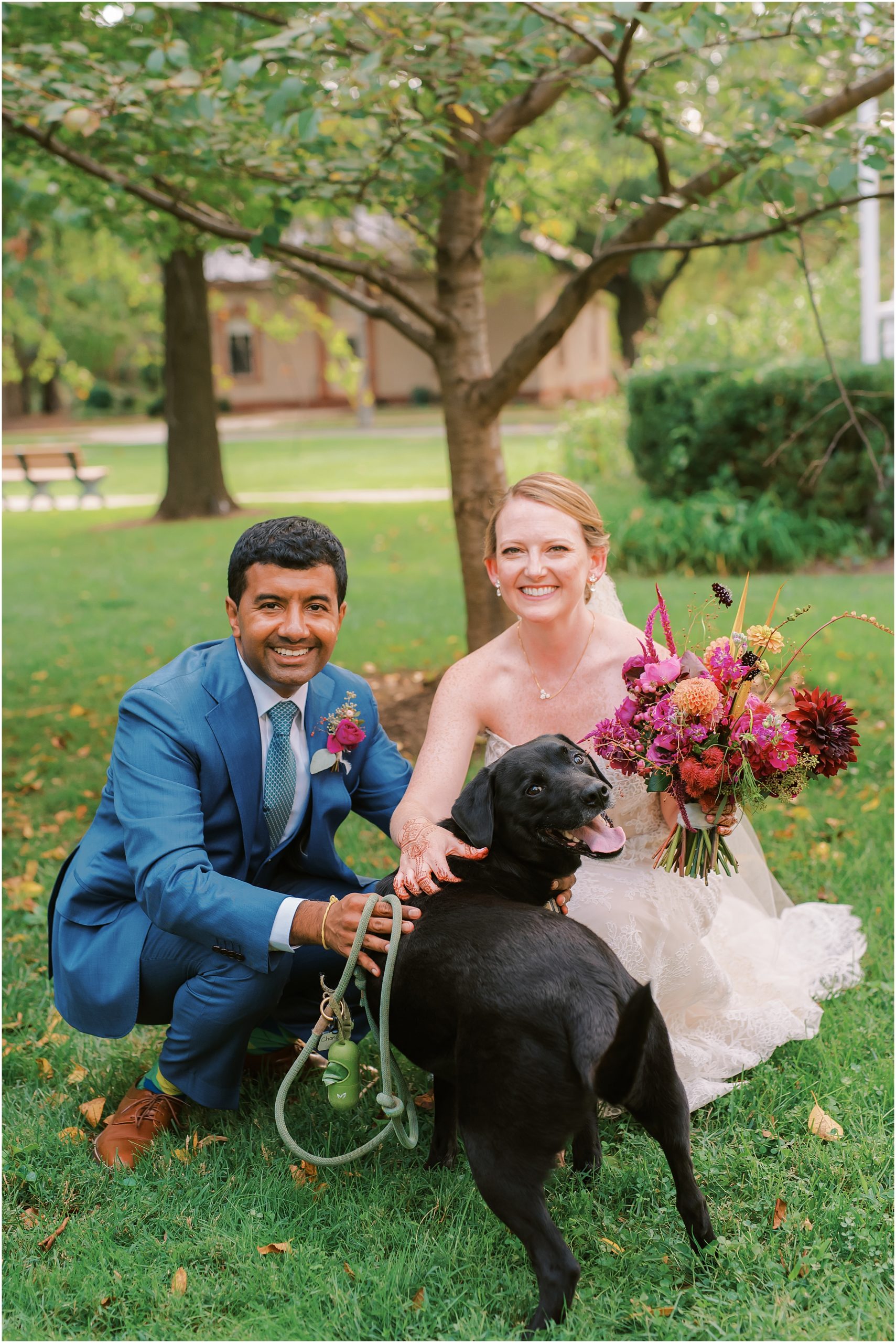Couple posing with their black lab on their wedding day