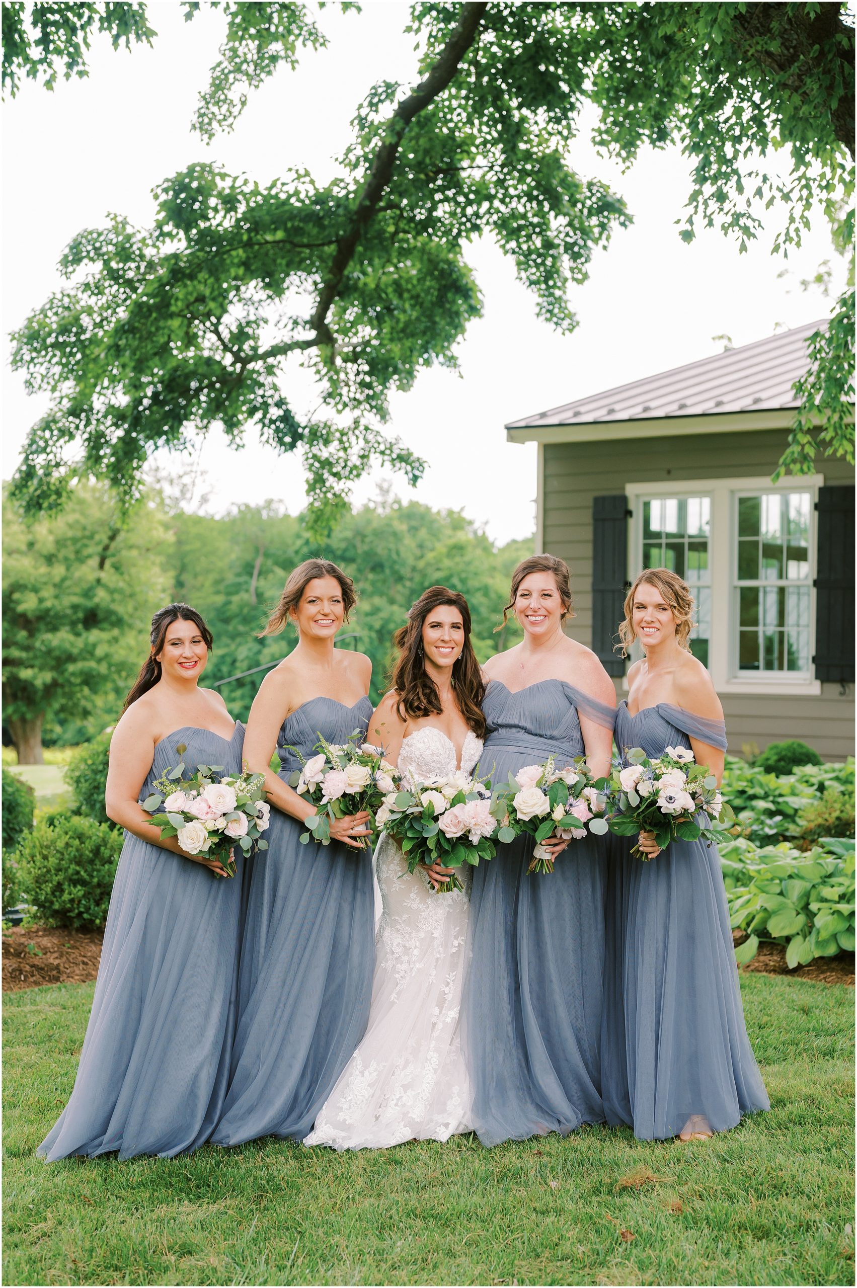 Bride with bridesmaids wearing strapless dusty blue bridesmaid dresses