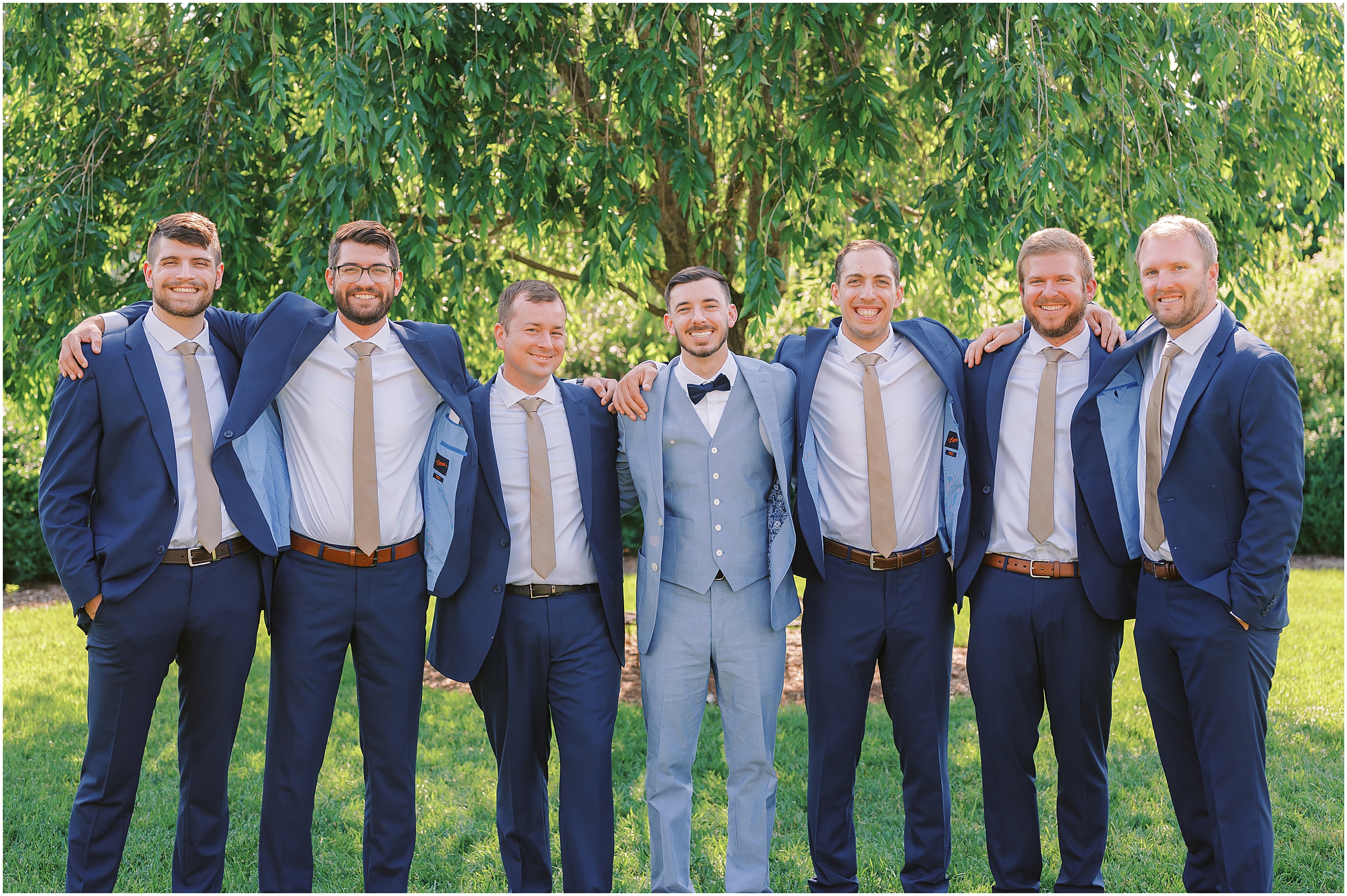 Groom and groomsmen in navy suits with gold ties