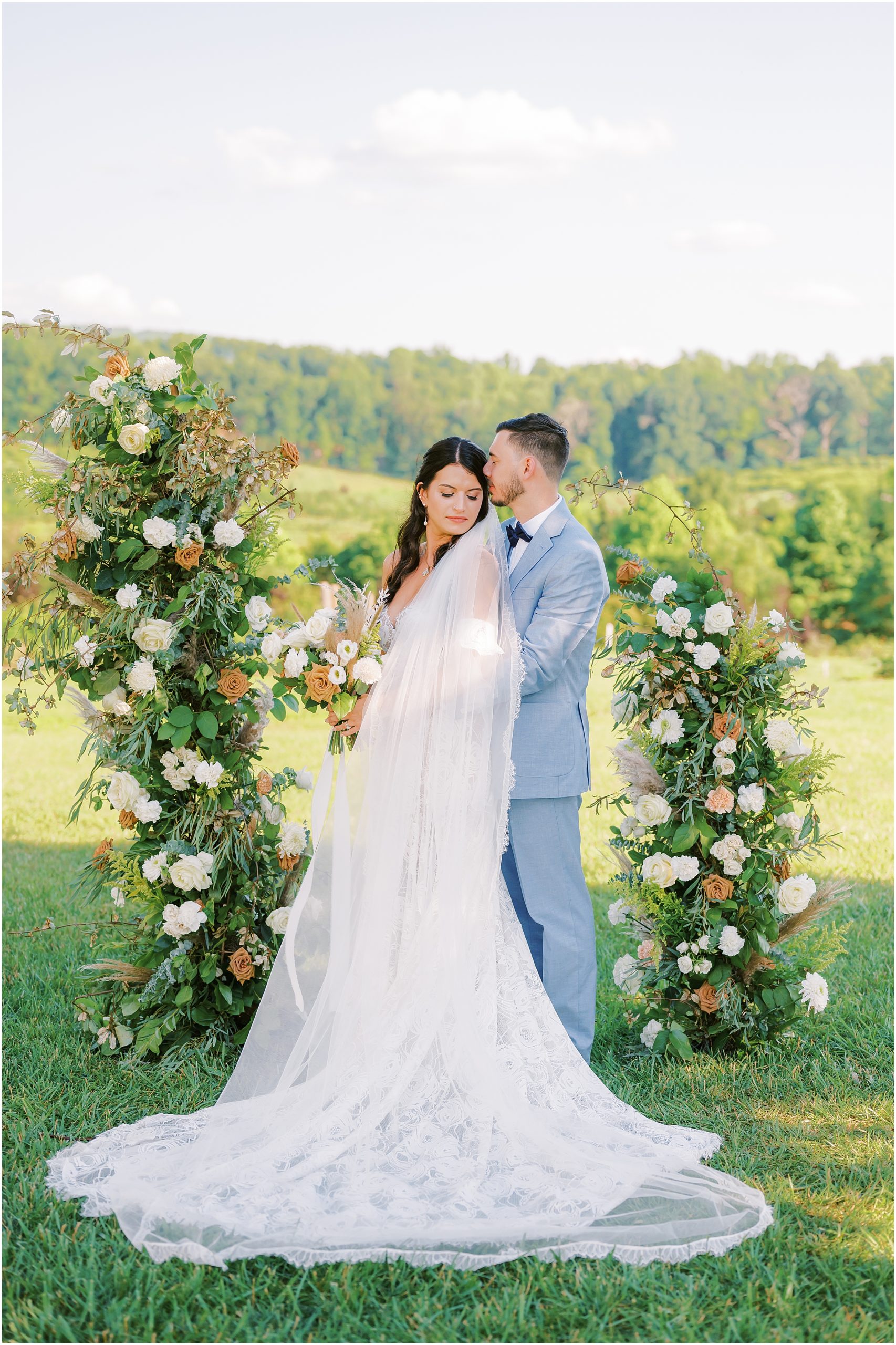 Newlywed portraits in front of summer floral arch